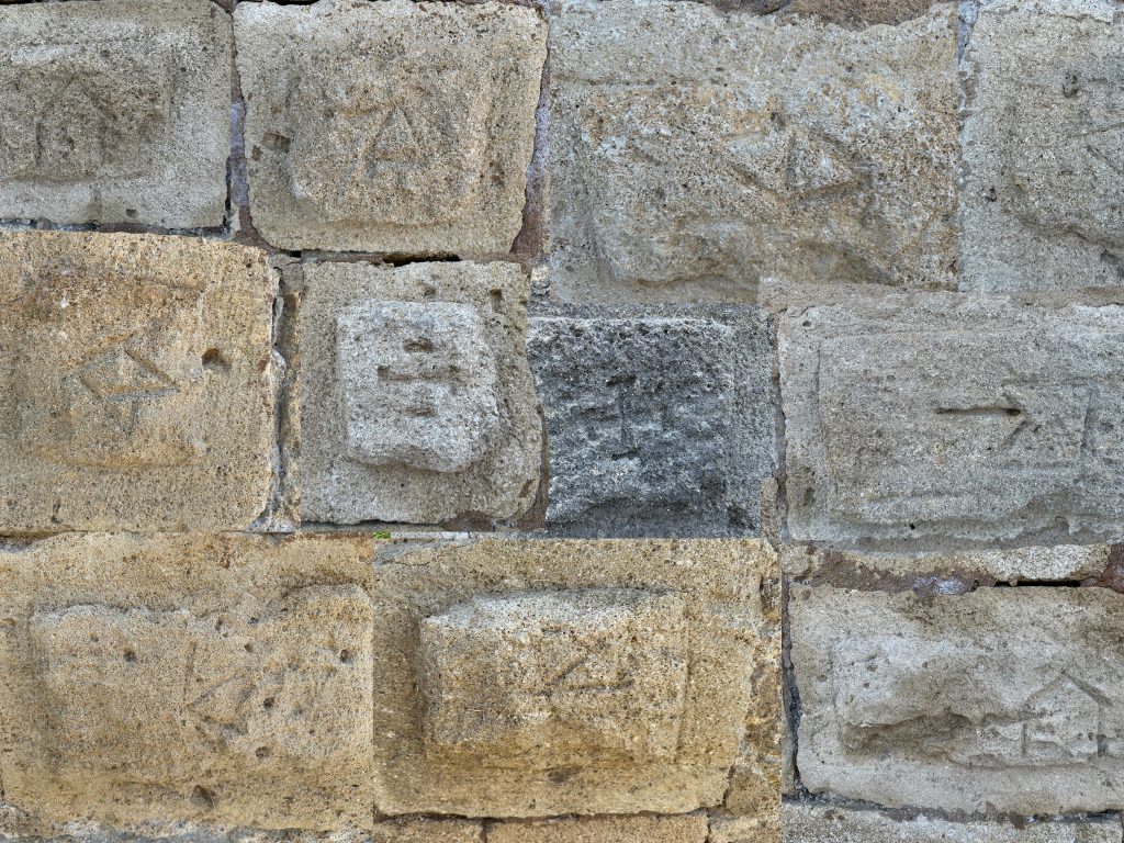 Marques de tâcherons sur les pierres des remparts d’Aigues-Mortes lors d’un safari Camargue Sauvage